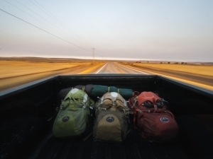 Three backpacks in the bed of a pickup truck