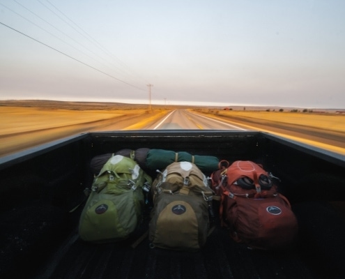 Three backpacks in the bed of a pickup truck